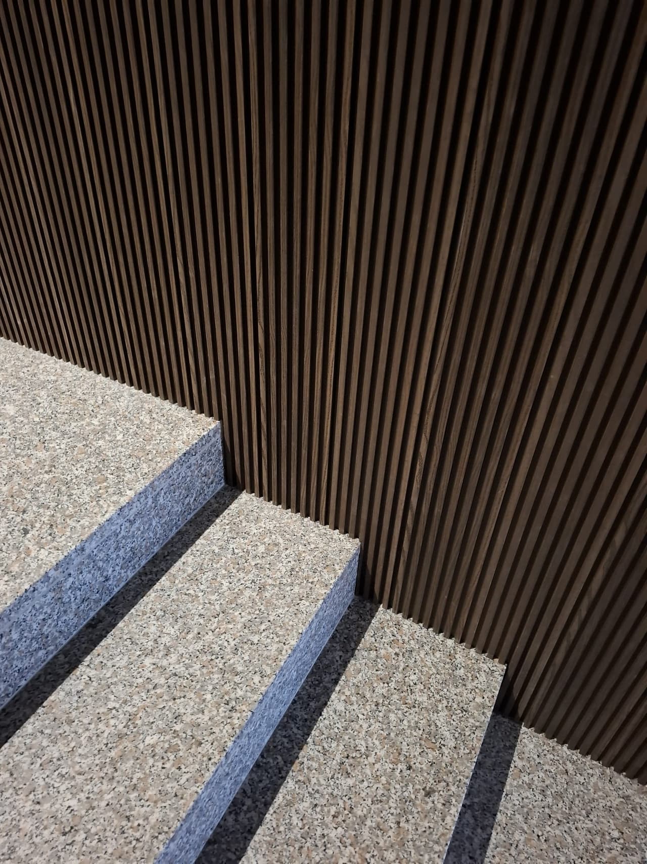 Rivestimento a doghe verticali in WPC e scala in granito