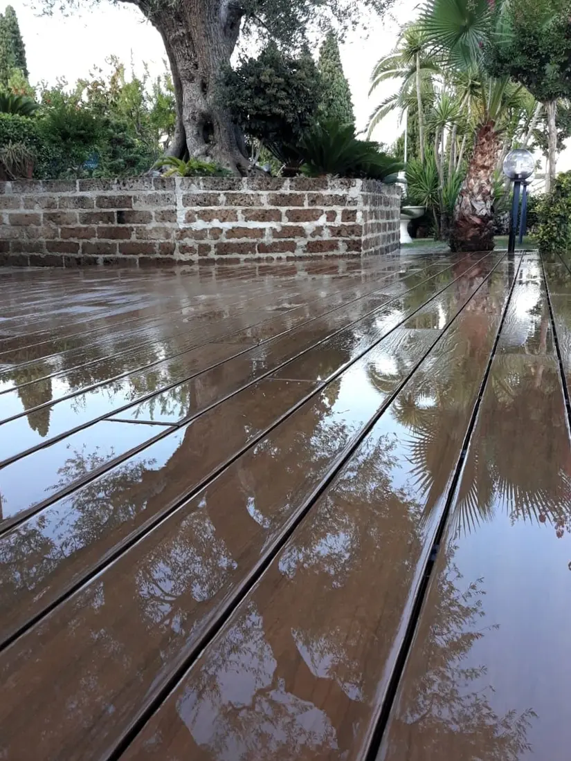 Decking WPC in giardino bagnato dalla pioggia con ulivo
