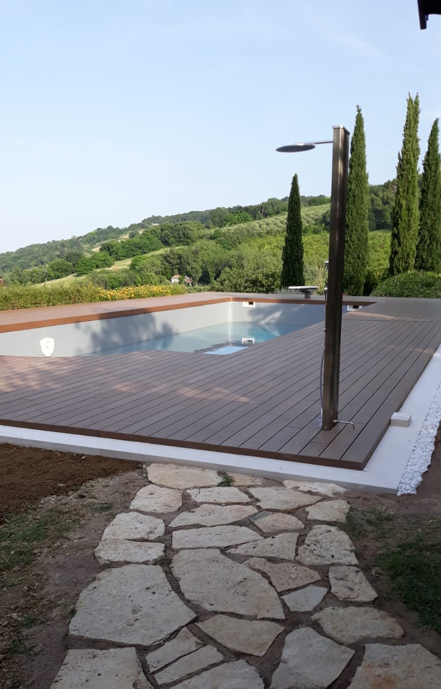 Piscina con bordo in WPC e doccia esterna, vista sulle colline