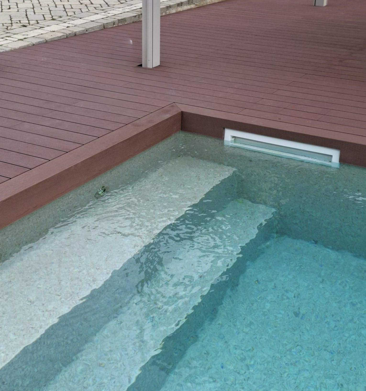 Bordo piscina in WPC con gradini di accesso all'acqua