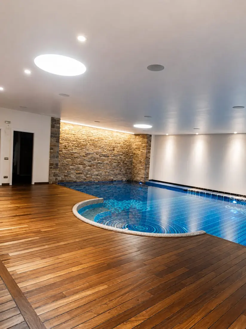 Piscina interna con decking in teak e mosaico blu